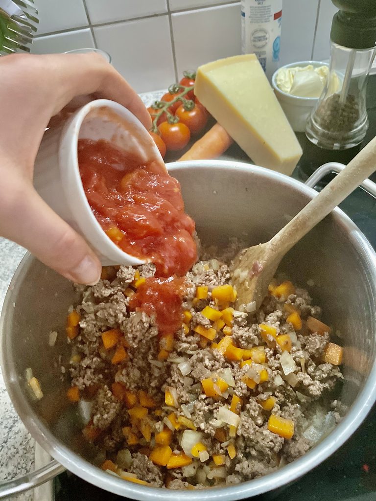 Ragù alla Bolognese mit passierten Tomaten vermengen